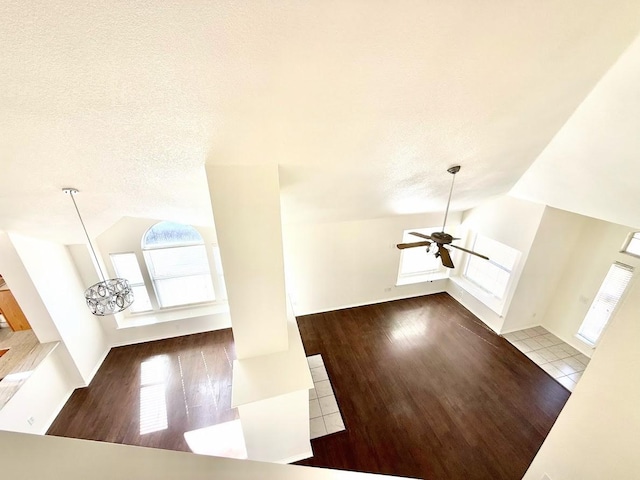 unfurnished living room featuring tile patterned flooring, ceiling fan, vaulted ceiling, and a textured ceiling