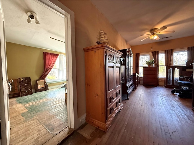 interior space with a wealth of natural light, wood-type flooring, ceiling fan, and vaulted ceiling