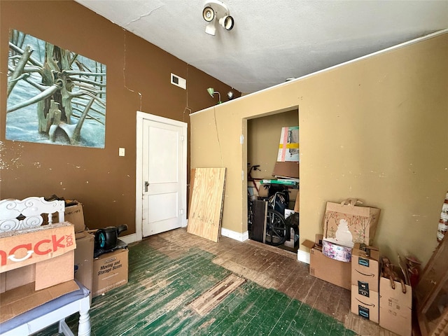 interior space featuring baseboards, visible vents, vaulted ceiling, and dark wood-type flooring