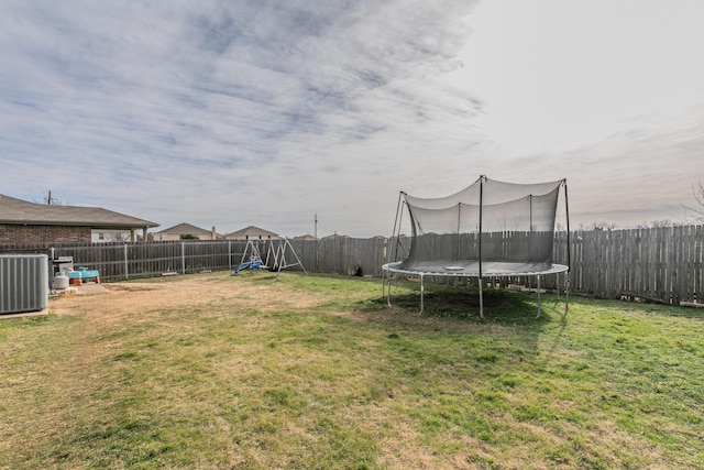 view of yard with a trampoline and central AC