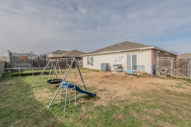 back of property with a playground, a yard, and a trampoline