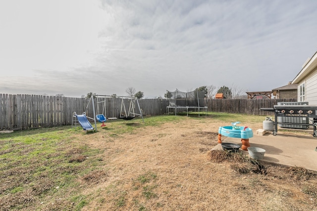 view of yard featuring a playground, a trampoline, and a patio area