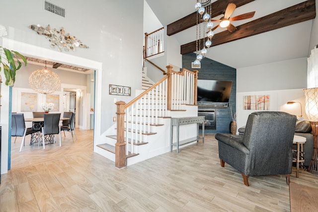 living room with a fireplace, light hardwood / wood-style flooring, high vaulted ceiling, and beamed ceiling