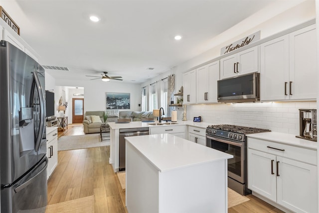 kitchen featuring stainless steel appliances, a center island, sink, and kitchen peninsula