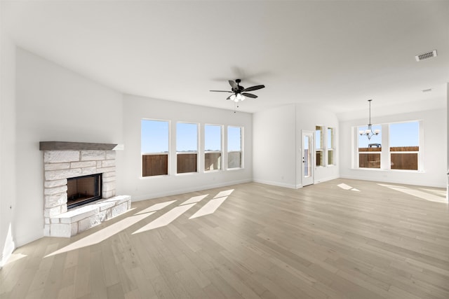 unfurnished living room with a stone fireplace, a wealth of natural light, and light wood-type flooring