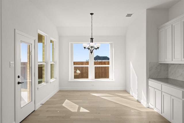 unfurnished dining area with lofted ceiling, light hardwood / wood-style floors, and a healthy amount of sunlight