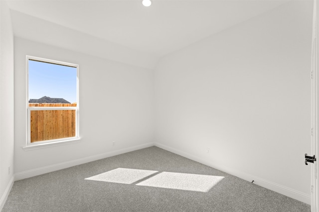 carpeted spare room with vaulted ceiling