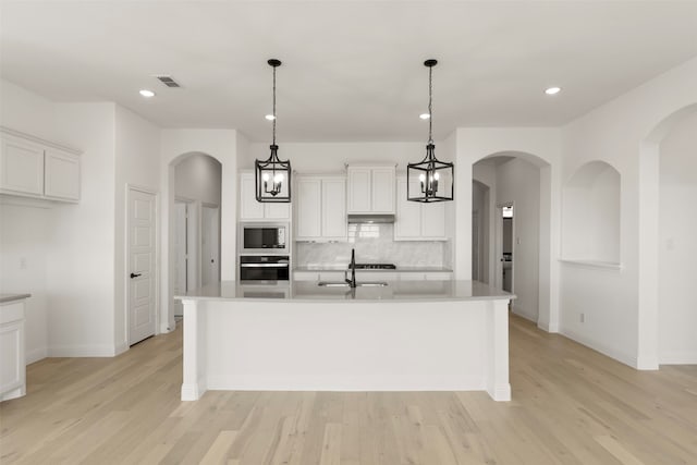 kitchen with an island with sink, appliances with stainless steel finishes, and white cabinets