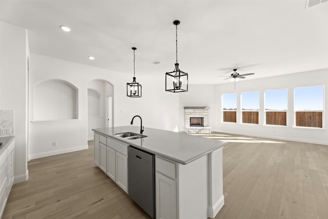 kitchen with pendant lighting, sink, a kitchen island with sink, light hardwood / wood-style floors, and stainless steel dishwasher