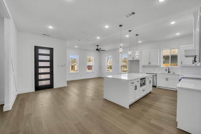 kitchen with white cabinetry, decorative light fixtures, and a kitchen island