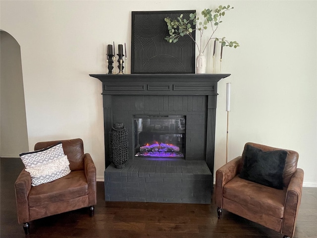 living area with dark wood-type flooring and a brick fireplace