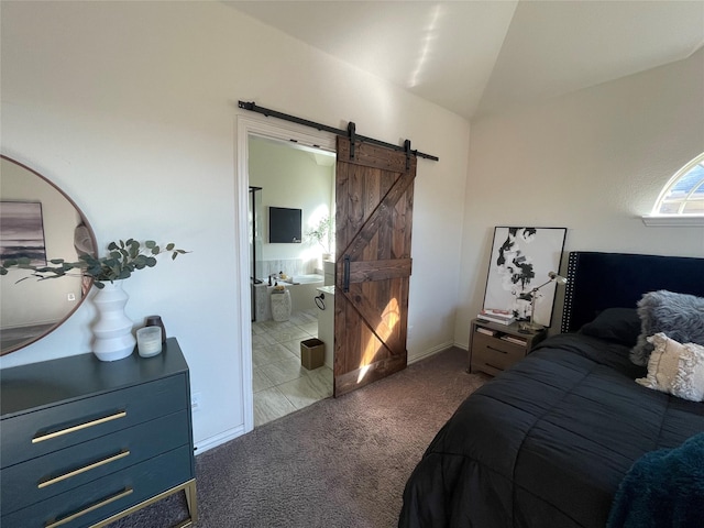 bedroom with carpet flooring, connected bathroom, a barn door, baseboards, and vaulted ceiling