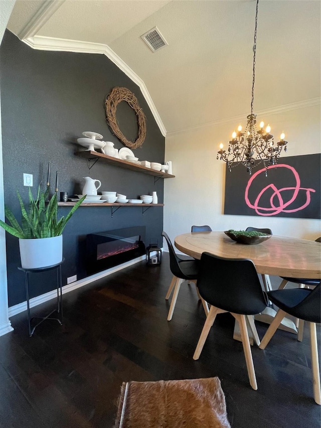 dining area with crown molding, vaulted ceiling, hardwood / wood-style floors, and a notable chandelier