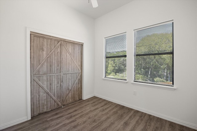 unfurnished bedroom with multiple windows, dark hardwood / wood-style flooring, and ceiling fan