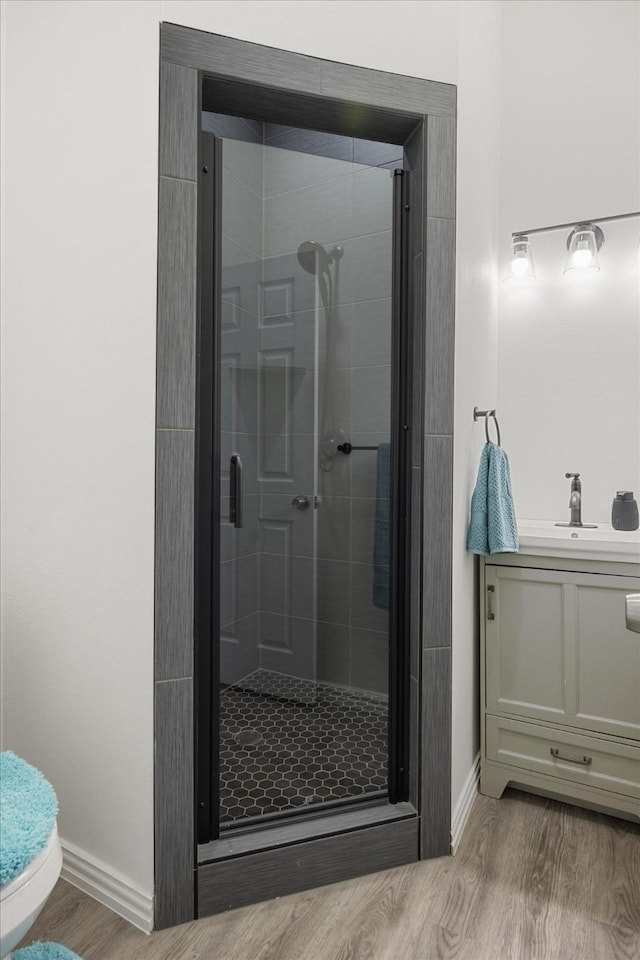 bathroom featuring walk in shower, sink, toilet, and hardwood / wood-style floors