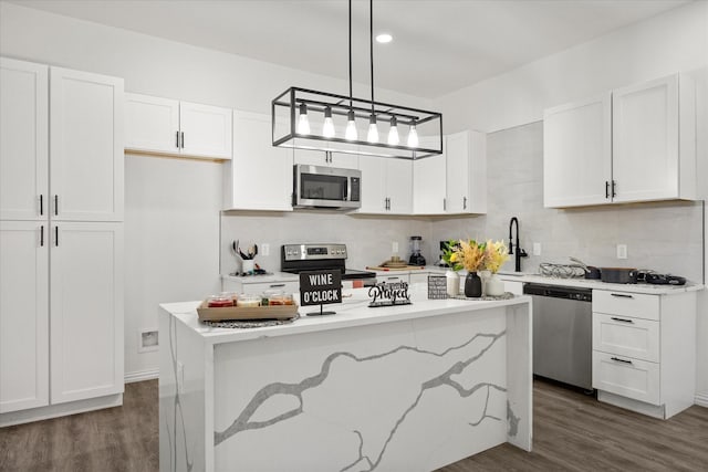 kitchen with dark wood-type flooring, decorative light fixtures, a center island, appliances with stainless steel finishes, and white cabinets