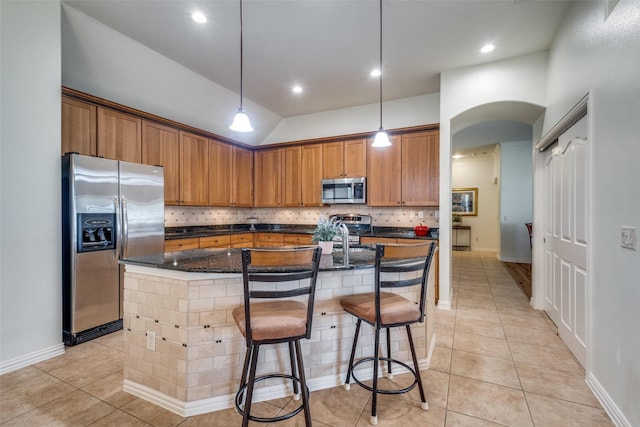 kitchen with a kitchen breakfast bar, an island with sink, and appliances with stainless steel finishes