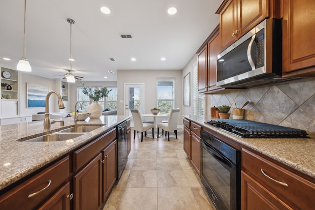 kitchen with sink, light stone counters, decorative light fixtures, decorative backsplash, and black appliances