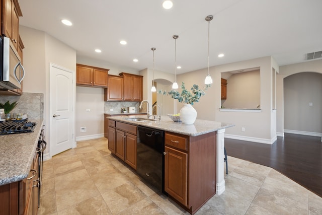 kitchen featuring light stone countertops, sink, a center island with sink, and black appliances