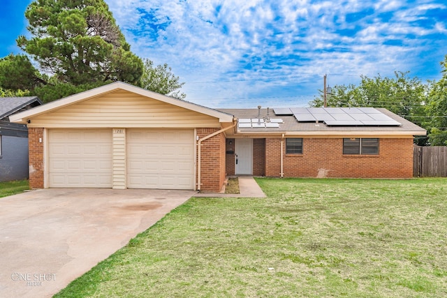 single story home with a garage, a front lawn, and solar panels