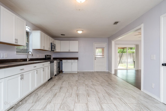 kitchen with sink, a textured ceiling, white cabinets, and appliances with stainless steel finishes