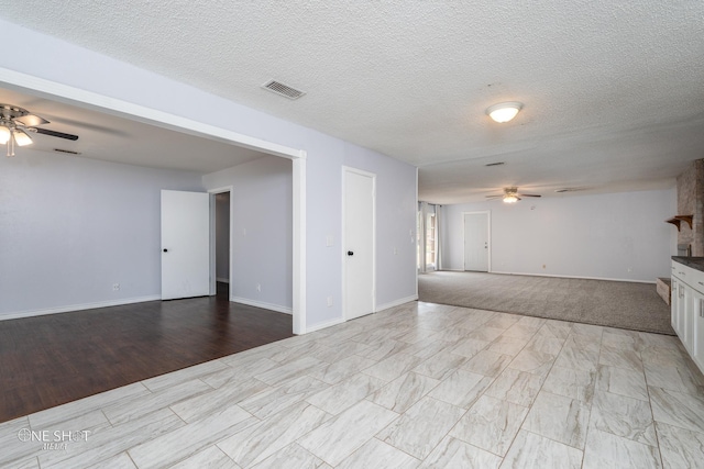 unfurnished living room with a textured ceiling and ceiling fan