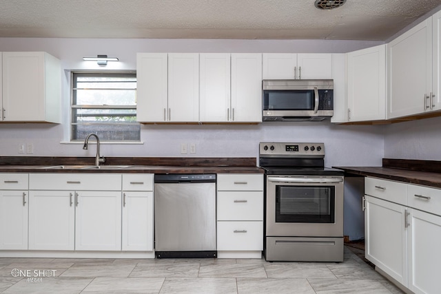 kitchen with stainless steel appliances, sink, white cabinets, and a textured ceiling