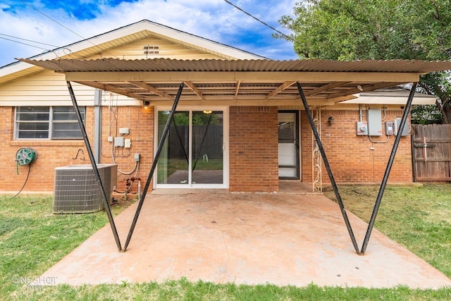 rear view of property with a carport, a patio, and central AC