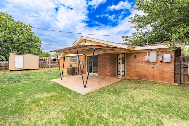 back of house with a storage shed, a yard, central AC, and a patio area