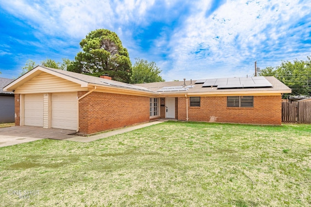 ranch-style home with a garage, solar panels, and a front lawn