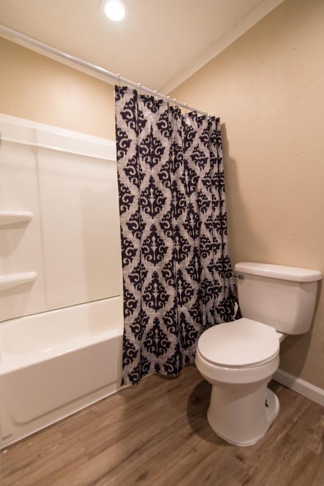 bathroom featuring shower / bathtub combination with curtain, toilet, and hardwood / wood-style floors