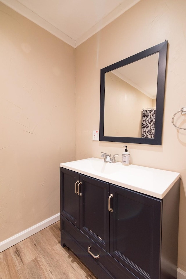 bathroom featuring vanity, wood-type flooring, and ornamental molding