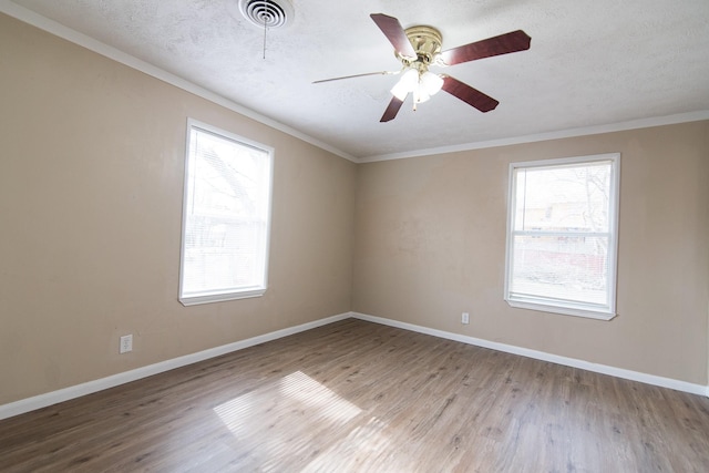 empty room with ornamental molding, a healthy amount of sunlight, ceiling fan, and light hardwood / wood-style flooring