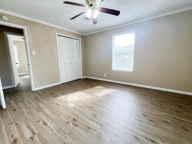 unfurnished bedroom featuring crown molding, light hardwood / wood-style flooring, ceiling fan, a textured ceiling, and a closet