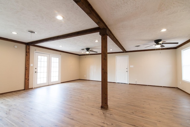 unfurnished living room with a healthy amount of sunlight, beam ceiling, light hardwood / wood-style floors, and a textured ceiling