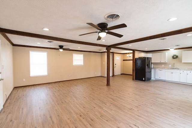 unfurnished living room featuring sink, ceiling fan, beamed ceiling, and light wood-type flooring