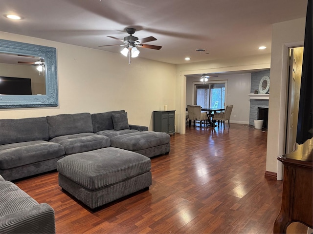 living room featuring a brick fireplace, dark hardwood / wood-style floors, and ceiling fan