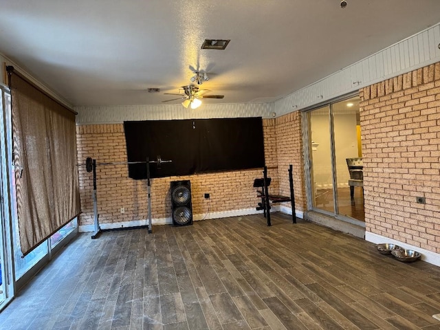 workout area featuring ceiling fan, brick wall, dark hardwood / wood-style flooring, and a textured ceiling