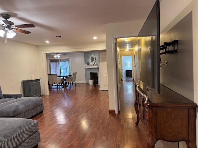 living room with a fireplace, dark hardwood / wood-style floors, and ceiling fan