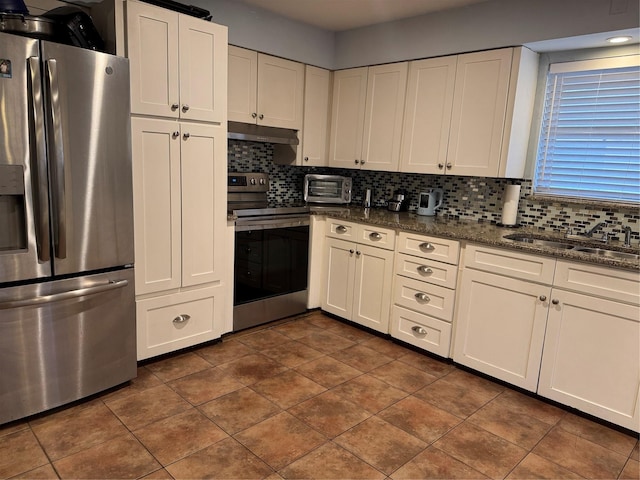 kitchen with white cabinets, stainless steel appliances, sink, and dark stone counters