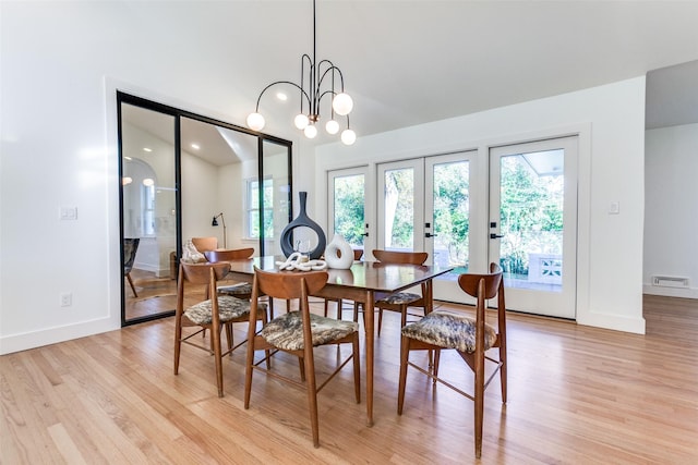 dining space featuring french doors, plenty of natural light, a chandelier, and light hardwood / wood-style flooring