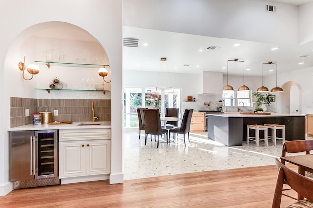 bar with pendant lighting, sink, backsplash, wine cooler, and white cabinets