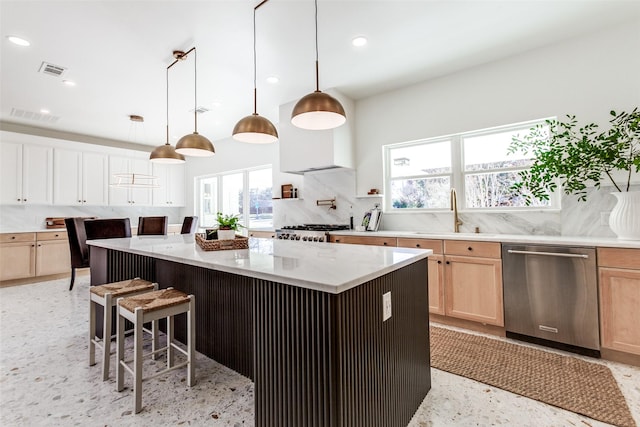 kitchen featuring sink, hanging light fixtures, dishwasher, a kitchen island, and stove