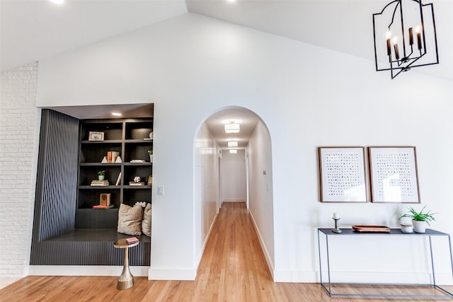 hallway with lofted ceiling, hardwood / wood-style floors, and built in features