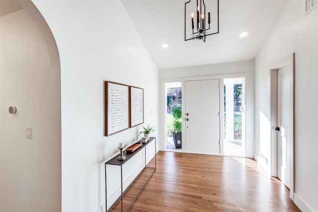 entryway featuring vaulted ceiling, a notable chandelier, and light wood-type flooring