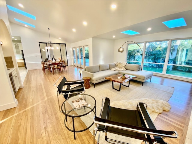 living room featuring french doors, vaulted ceiling, an inviting chandelier, and light hardwood / wood-style flooring