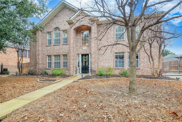 traditional-style home featuring brick siding and fence