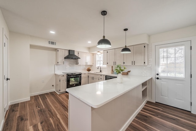 kitchen with wall chimney exhaust hood, kitchen peninsula, white cabinets, and black appliances