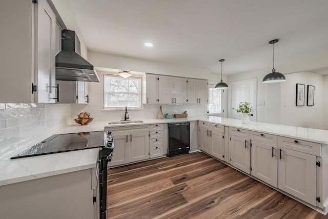 kitchen featuring sink, dishwasher, hanging light fixtures, dark hardwood / wood-style flooring, and wall chimney exhaust hood