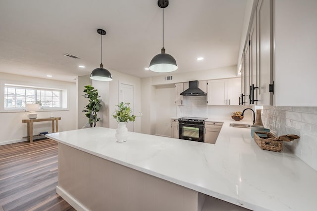 kitchen with pendant lighting, sink, kitchen peninsula, black range with electric stovetop, and wall chimney range hood